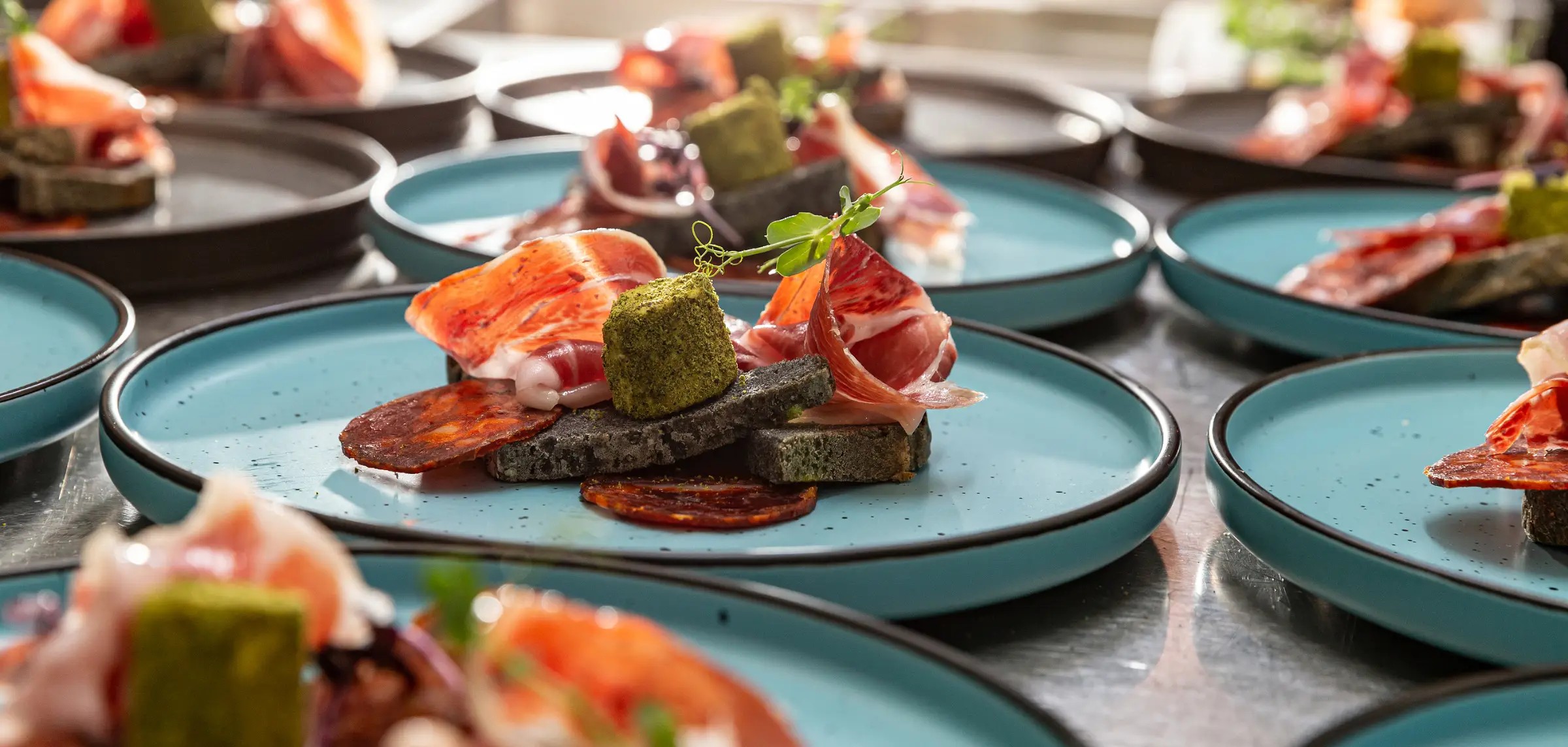party food on a blue plate with ham and sausages